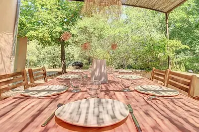 a wooden table with plates and glasses on it at La maison Calavoun in Maubec
