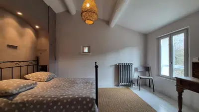 a bedroom with a bed and a window and a lamp at La maison Calavoun in Maubec