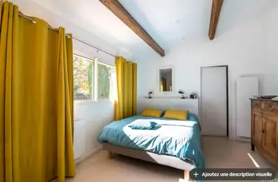 a bedroom with a bed with yellow curtains in it at Maison et studio avec vue panoramique et piscine in La Bastidonne