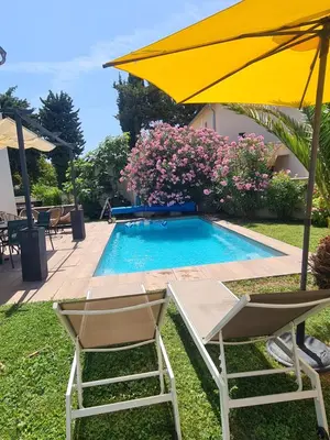 a yellow umbrella and two chairs and a swimming pool at Villa KAMARO in LʼIsle-sur-la-Sorgue