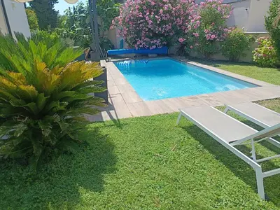a swimming pool in a yard with a bench and flowers at Villa KAMARO in LʼIsle-sur-la-Sorgue