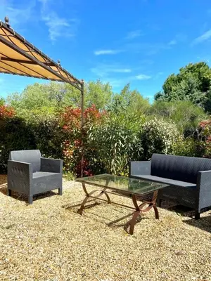 a patio with two chairs and a table and an umbrella at La Clemensane in Lacoste