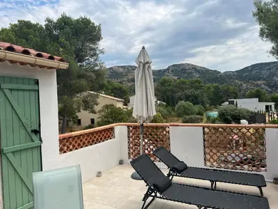 a patio with two chairs and an umbrella on a balcony at Appartement T2 dans le Luberon in Cavaillon
