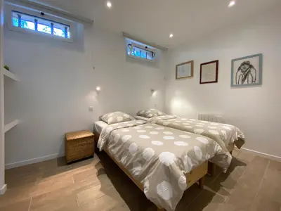 two beds in a white room with two windows at Chez Pascal et Marion in La Tour-dʼAigues