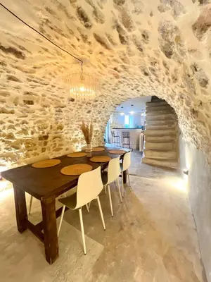 a dining room with a table and a stone wall at Authentique et paisible maison de village in Bédoin