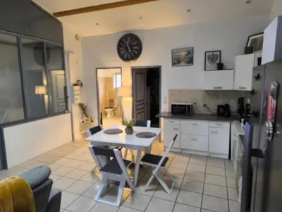 a kitchen with a table and chairs and a clock on the wall at Appartement provençal in Vedène