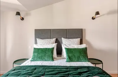 a bedroom with a bed with green and white pillows at Le fort 7 Appart centre ville in LʼIsle-sur-la-Sorgue