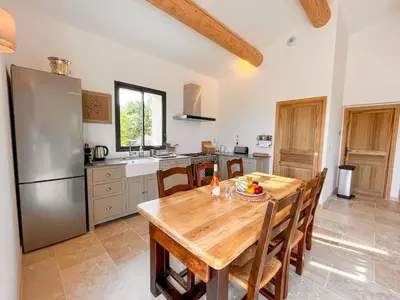 a kitchen with a wooden table and a stainless steel refrigerator at Maison de charme 4 étoiles - superbe vue et bassin-piscine privé in Rustrel