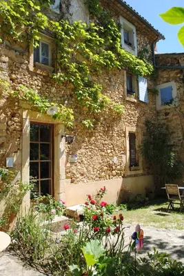 a stone building with flowers in front of it at Chambres d'Hôtes Istrane in Rustrel