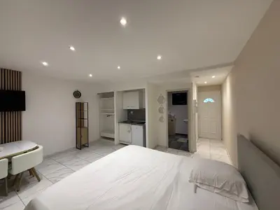 a bedroom with a large white bed and a kitchen at Appart hotel bonpas in Noves