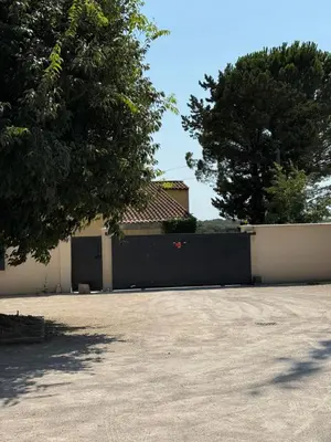 a fence with a black gate in front of a house at Appart hotel bonpas in Noves