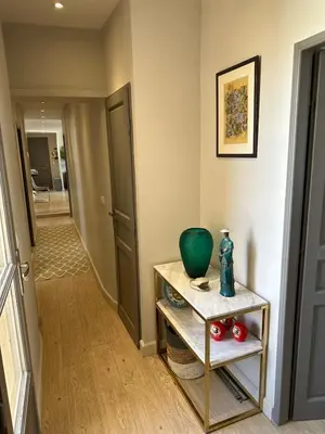 a hallway with a table with a green vase on it at Aix flat in historic center, 17th century building in Aix-en-Provence