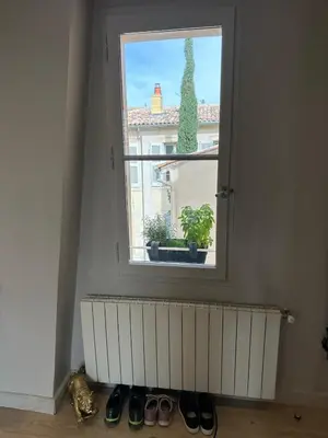 a window with a radiator and some shoes in a room at Aix flat in historic center, 17th century building in Aix-en-Provence
