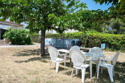 a table and chairs under a tree in a yard at Maison Familiale Piscine et Proche des commerces in Pertuis