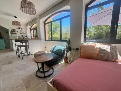 a bedroom with a bed and a table and some windows at Aix-en-Provence, Cosy studio au calme de la campagne avec Spa et Clim in Aix-en-Provence