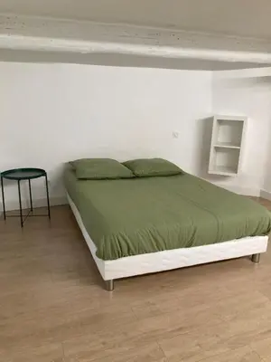 a bed in a white room with a black table at Appartement rénové plein centre in Aix-en-Provence