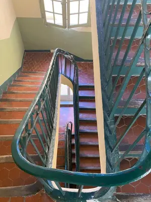 a spiral staircase with a green metal railing at Appartement rénové plein centre in Aix-en-Provence
