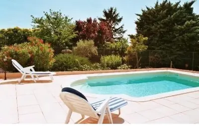 a swimming pool with two chairs and a table at Ferme au pied du luberon in Lourmarin