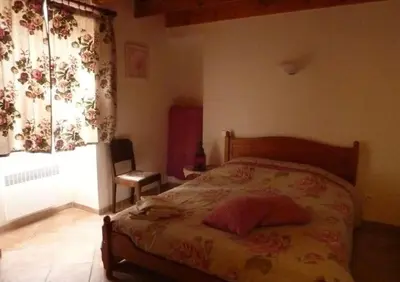 a bedroom with a bed and a window with curtains at Ferme au pied du luberon in Lourmarin