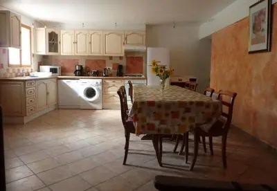 a kitchen with a table and chairs and a kitchen with a washing machine at Ferme au pied du luberon in Lourmarin