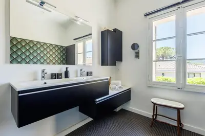 a bathroom with a black and white sink and a stool at Villa du Val - Welkeys in Aix-en-Provence