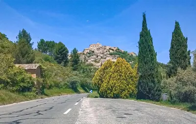 an empty road with a castle on top of a hill at Maison Avec Piscine in La Tour-dʼAigues