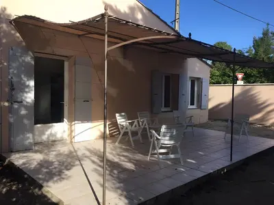 a patio with chairs and a table under an umbrella at Gîte En Provence, 90 M² in Vedène