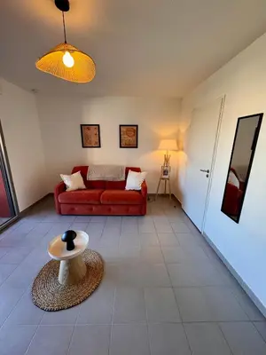 a living room with a red couch and a table at Terrasse, clim et piscine à Aix-en-Provence in Aix-en-Provence