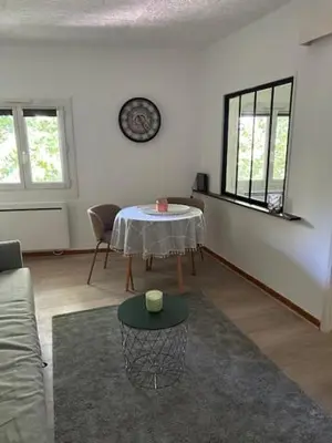 a living room with a table and a clock on the wall at Cocon douillet près du Cours Sextius in Aix-en-Provence