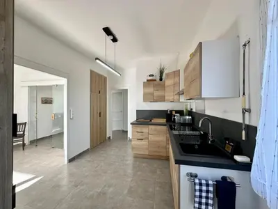 a kitchen with white cabinets and a black counter top at Villa Maguy - Piscine et jardin privée - Proche centre ville Aix en Provence - Parking - Boulodrome - Plancha in Aix-en-Provence