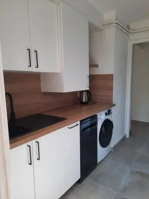 a kitchen with white cabinets and a black dishwasher at Appartement Le Cézanne in Aix-en-Provence