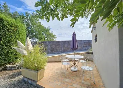 a patio with a table and chairs and an umbrella at La maison de Raffi in La Tour-dʼAigues