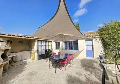 a patio with a table with chairs and an umbrella at La maison de Raffi in La Tour-dʼAigues