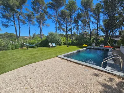 a swimming pool in a yard with a hammock at Villa sous les pins in Ventabren