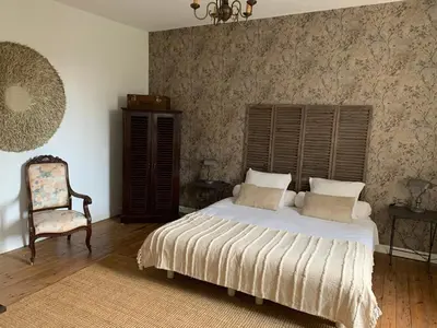 a bedroom with a large bed and a chair at Château Sainte BARBE in Loriol-du-Comtat