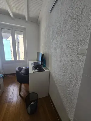 a room with a desk with a computer on a wall at Maison de village chaleureuse in Sainte-Tulle