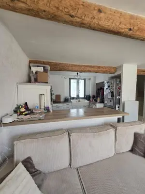 a living room with a couch and a kitchen at Maison de village chaleureuse in Sainte-Tulle