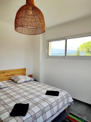 a bedroom with a bed and a large window at Le Picholine in Mazan