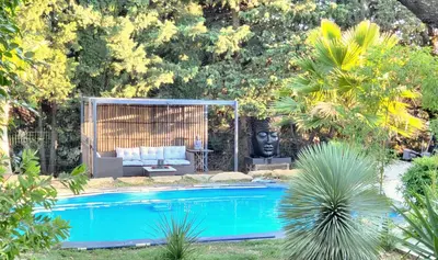 a swimming pool in a garden with a couch and a table at Pasca'land in Velaux