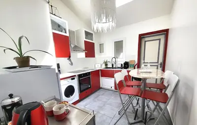 a kitchen with red cabinets and a table with chairs at Pasca'land in Velaux