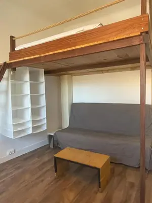 a bedroom with a bunk bed and a coffee table at Studio climatisé au centre du village in Saint-Michel-lʼObservatoire