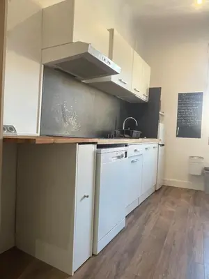 a kitchen with white cabinets and a counter top at Studio climatisé au centre du village in Saint-Michel-lʼObservatoire