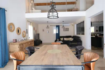 a dining room and living room with a wooden table and chairs at Luxury air-conditioned villa pool views Aix-en-Provence LS7-457 in Saint-Cannat