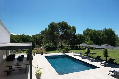 a swimming pool with chairs and umbrellas in a yard at Luxury air-conditioned villa pool views Aix-en-Provence LS7-457 in Saint-Cannat