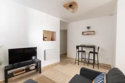 a living room with a couch and a tv and a table at Suite Lueur de Sable - Hypercentre - WiFi in Apt