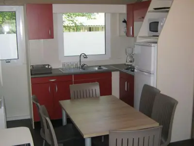 a small kitchen with a wooden table and a refrigerator at Chalet 46m² avec Terrasse à Noves - API-1-52-531 in Noves