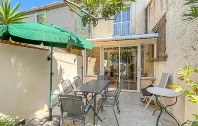 a patio with a table and chairs and an umbrella at Proche Alpilles in Eyragues