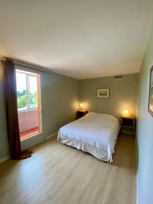 a bedroom with a white bed and a window at Le Pré de la Reyne in Sault-de-Vaucluse