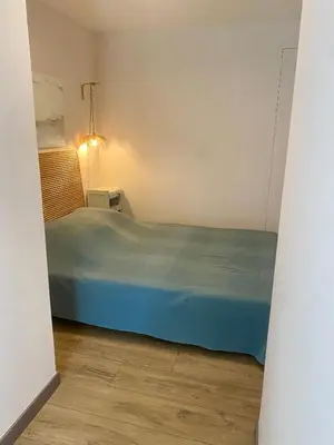 a small bedroom with a blue bed and a lamp at Le Pré de la Reyne in Sault-de-Vaucluse