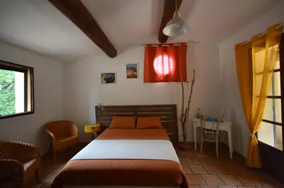 a bedroom with a bed and a table and a window at Les Chambres du Luberon & Table d'hôtes in Lauris